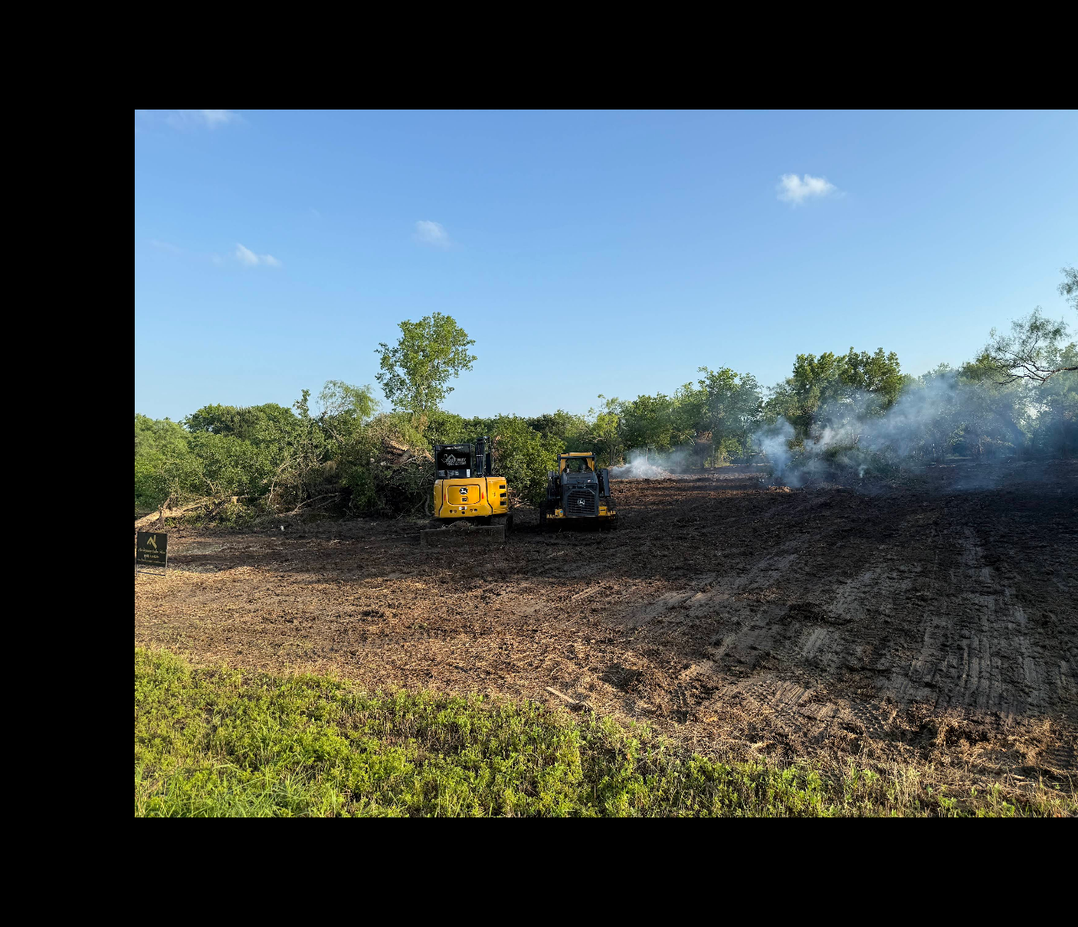 Active land clearing equipment working through brush and trees on Texas property