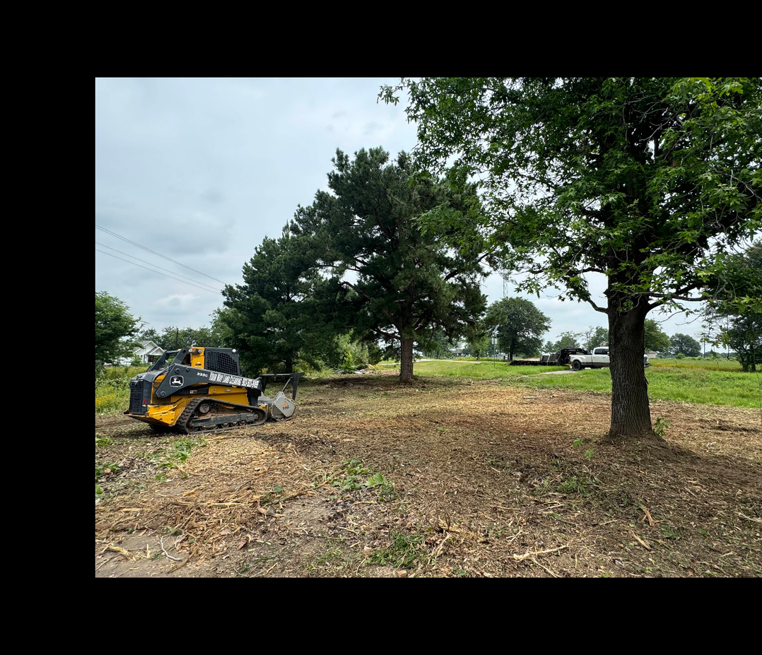 Compact track loader cleaning brush and trees on a rural Texas jobsite